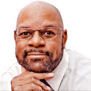 A bald man with a beard wearing glasses and a white shirt.