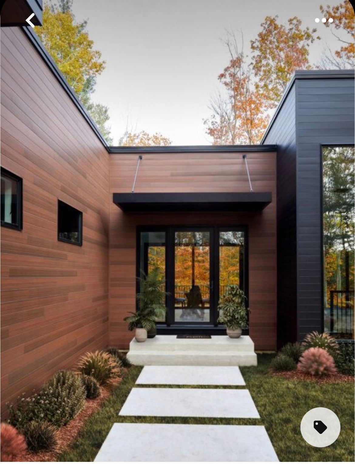 Wooden front door with sidelights and transom, gray siding, and brick accents.