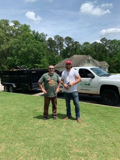 Two men are standing in front of a dump truck.