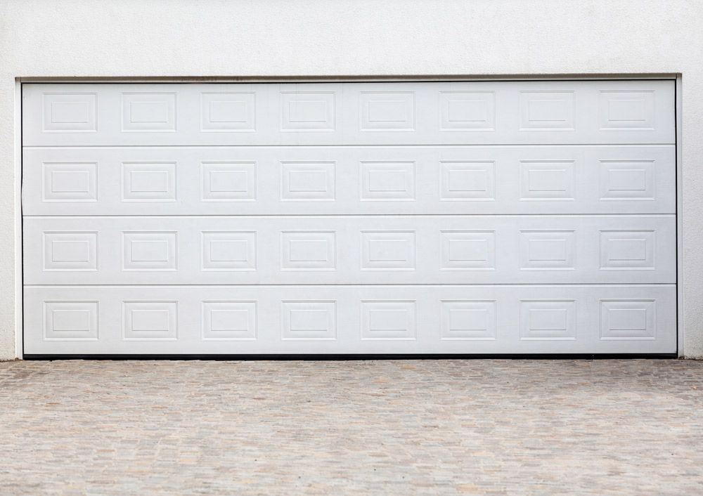 A White Garage Door is Sitting on Top of a Brick Driveway — Hastings Garage Door Services in Port Macquarie