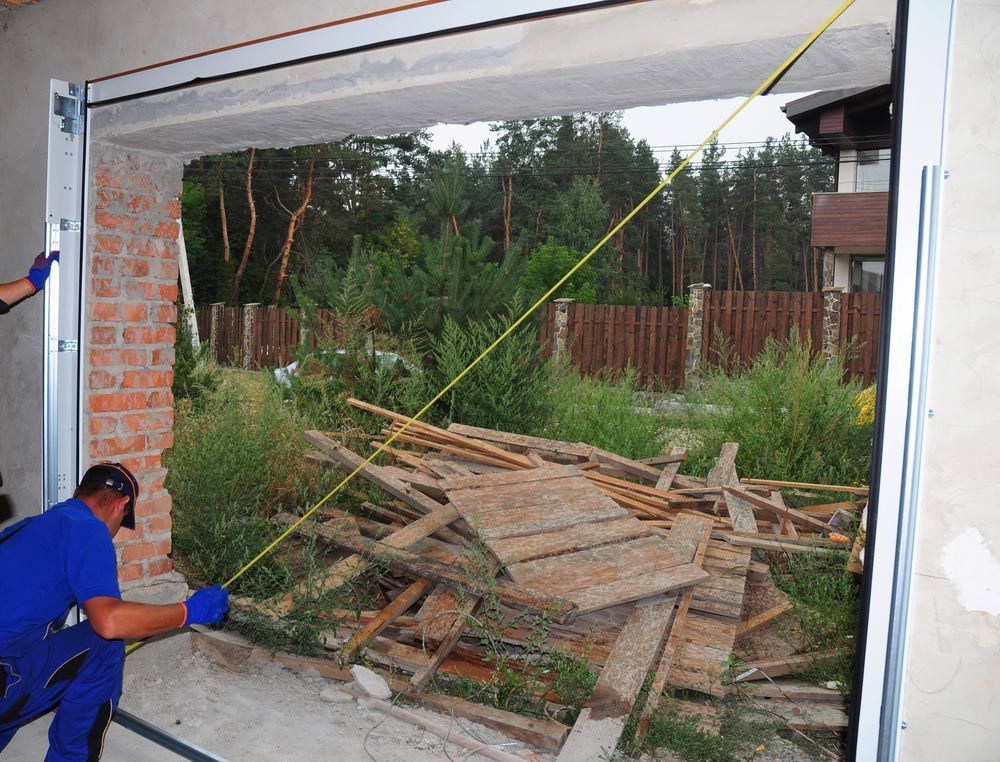 A Man is Measuring a Garage Door With a Tape Measure — Hastings Garage Door Services in Wauchope