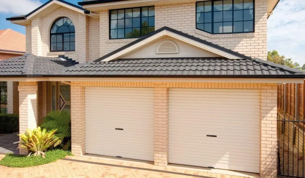 A Large Brick House With Two Garage Doors and a Black Roof — Hastings Garage Door Services in Port Macquarie