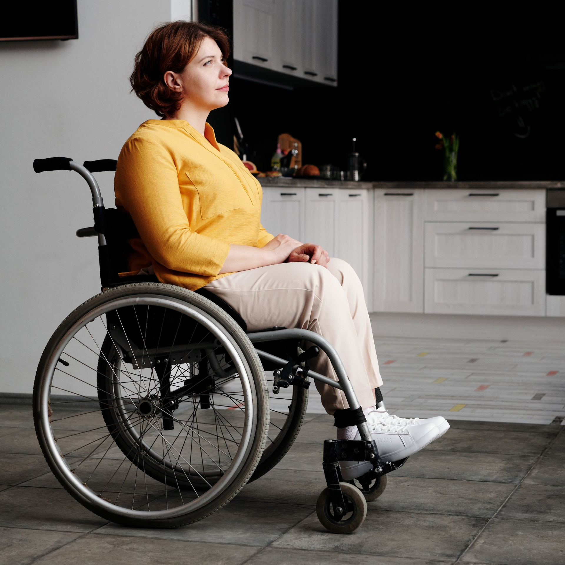 A woman in a yellow shirt is sitting in a wheelchair