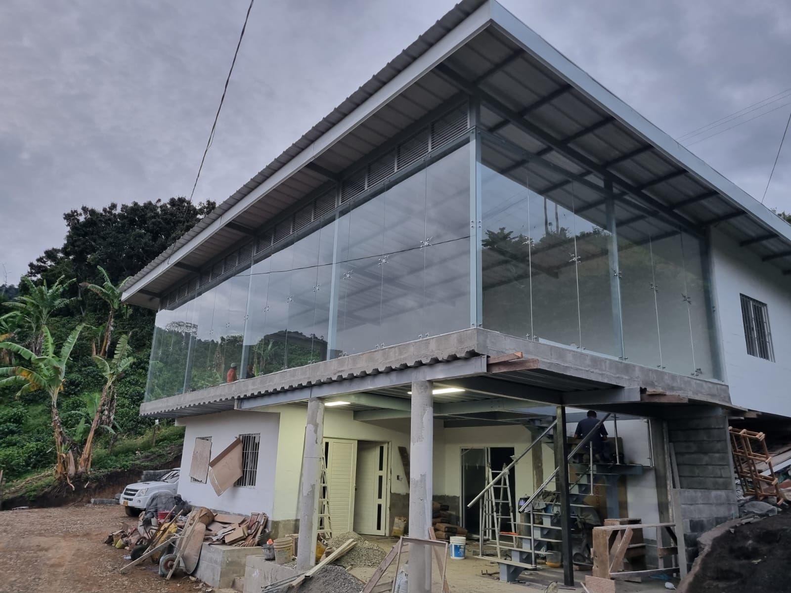 Edificio de dos plantas en construcción, con una gran planta superior acristalada y una planta baja parcialmente terminada.