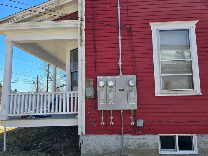 Red house exterior with utility meters, porch, and a white-trimmed window.