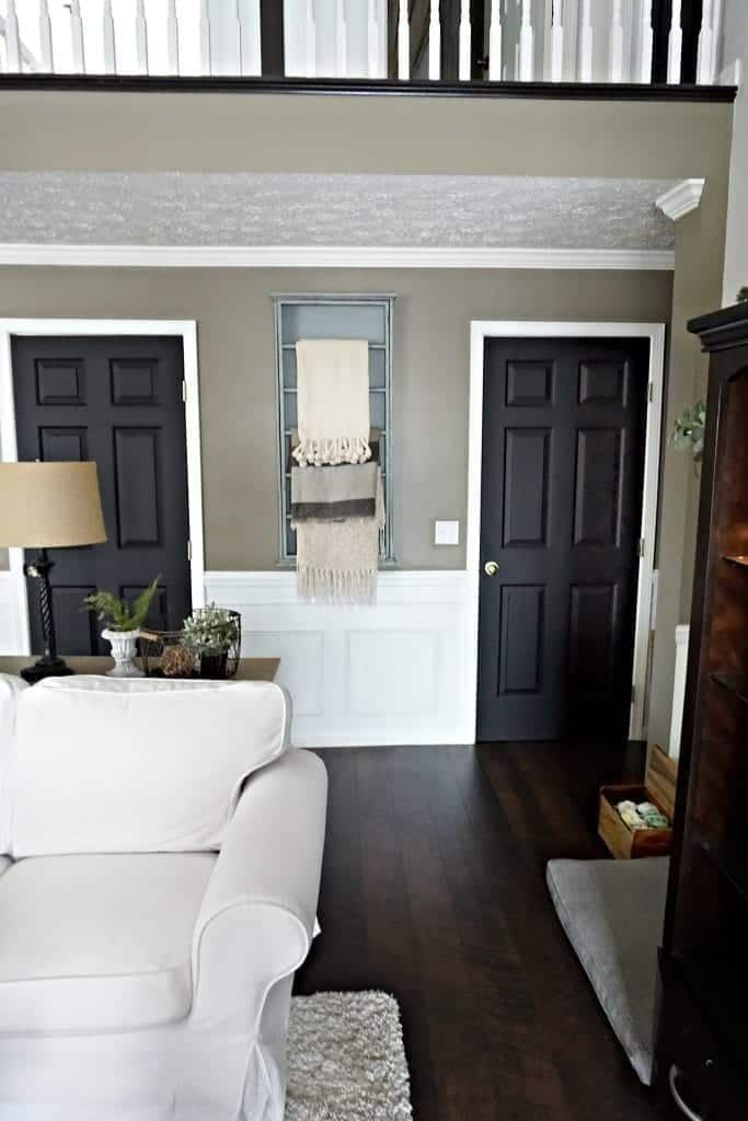 Living room with white sofa, dark doors, wood floors, and neutral walls.