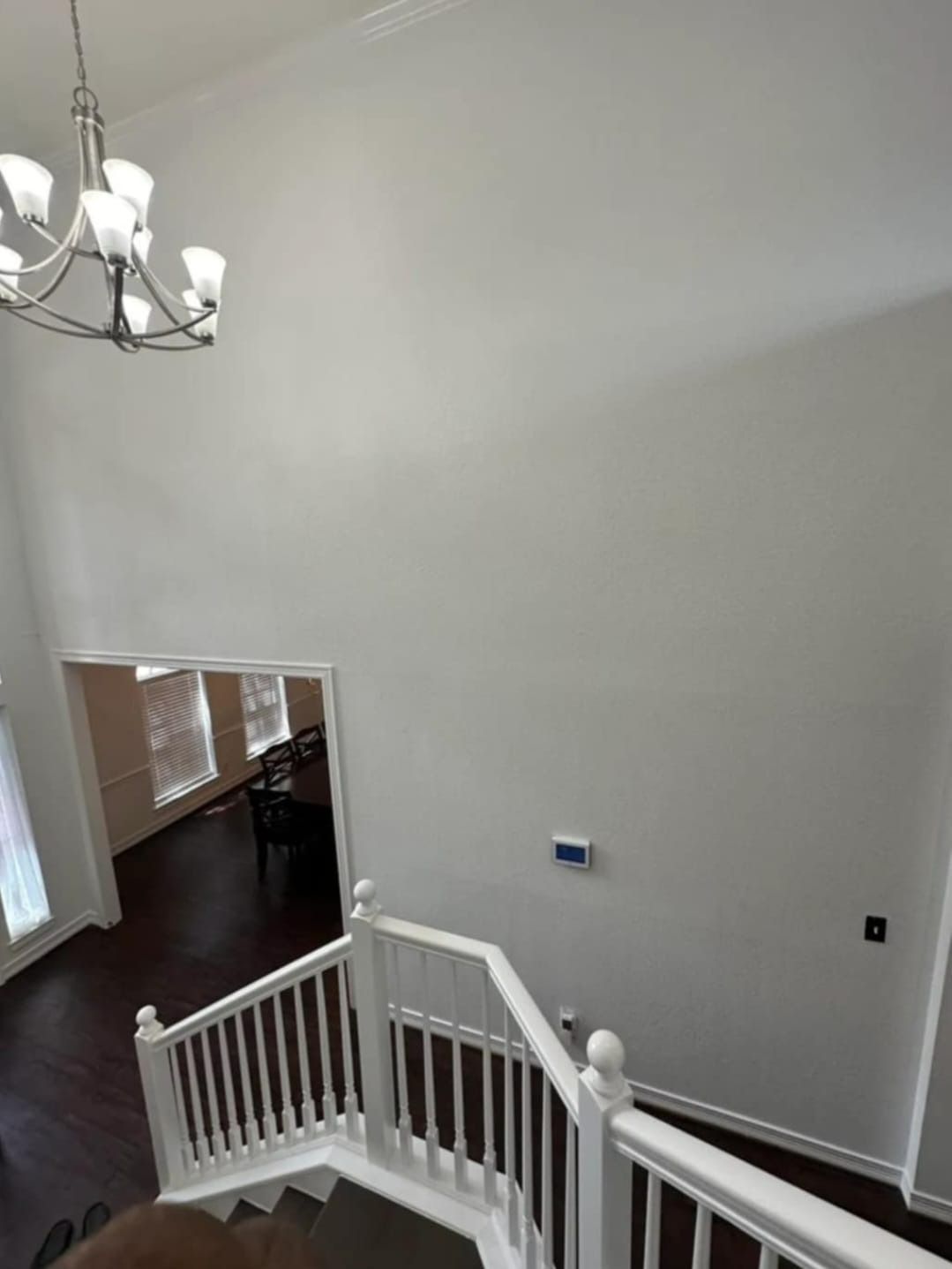 High-ceiling entryway with a chandelier, staircase, and view into a dining room.