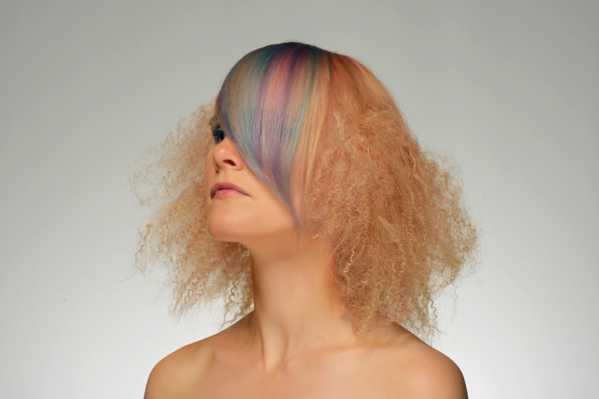 Eine Frau mit buntem Haar bedeckt ihr Gesicht mit ihrem Haar.