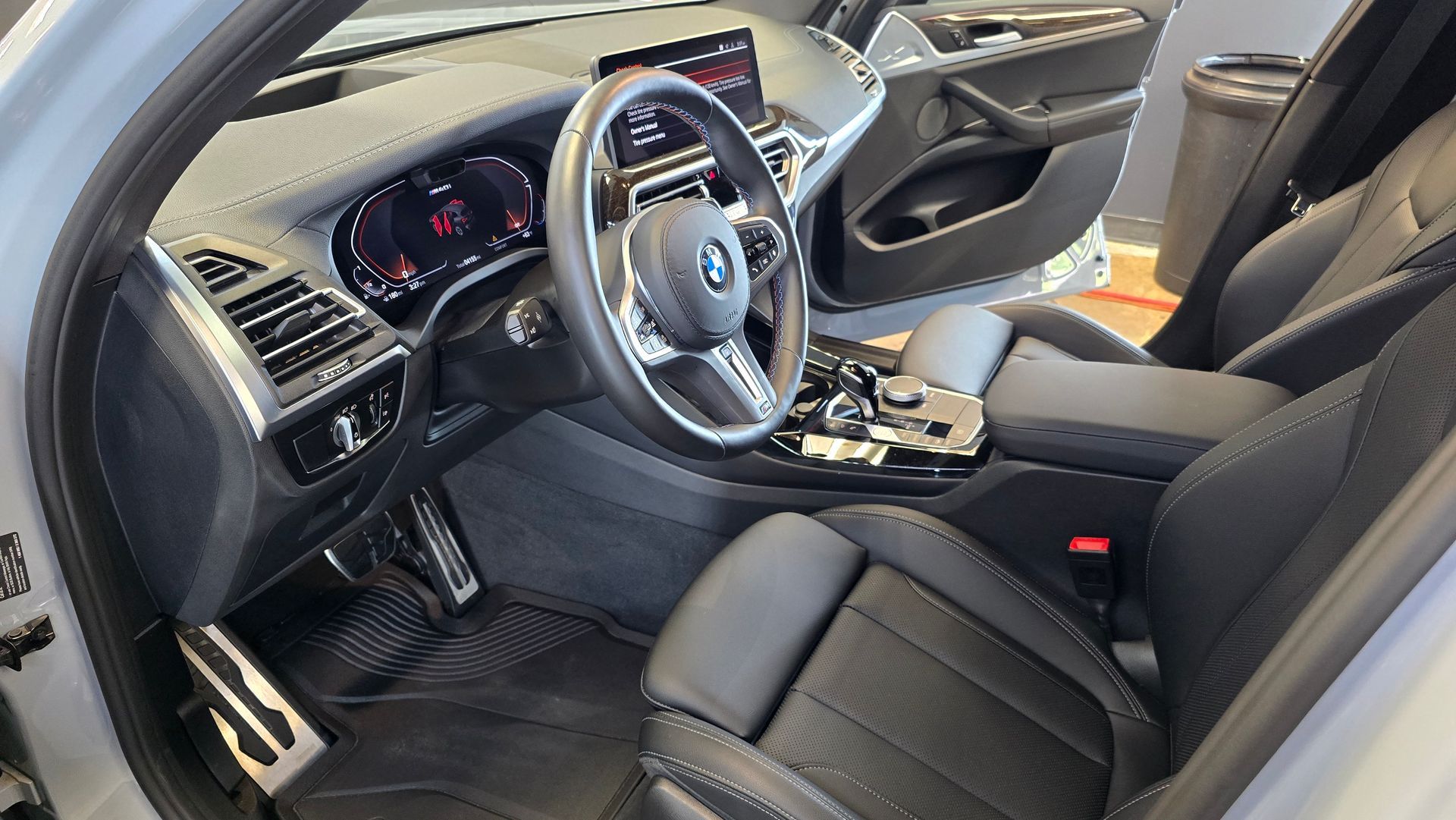 Interior of a gray BMW SUV with black leather seats and digital dashboard. Steering wheel is centered.