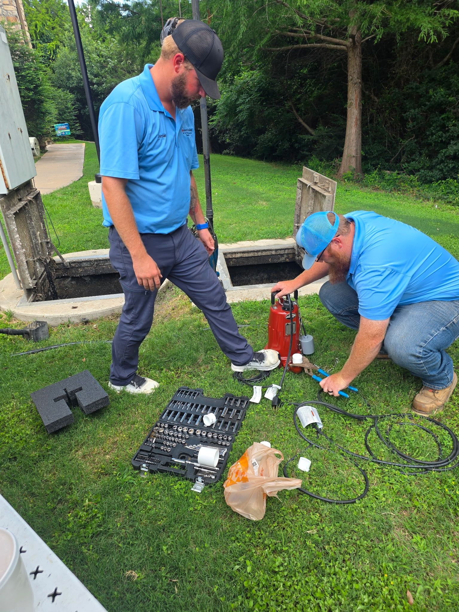 Outdoor yard with a concrete pad and green buckets, while a person in a blue shirt stands nearby taking a photo