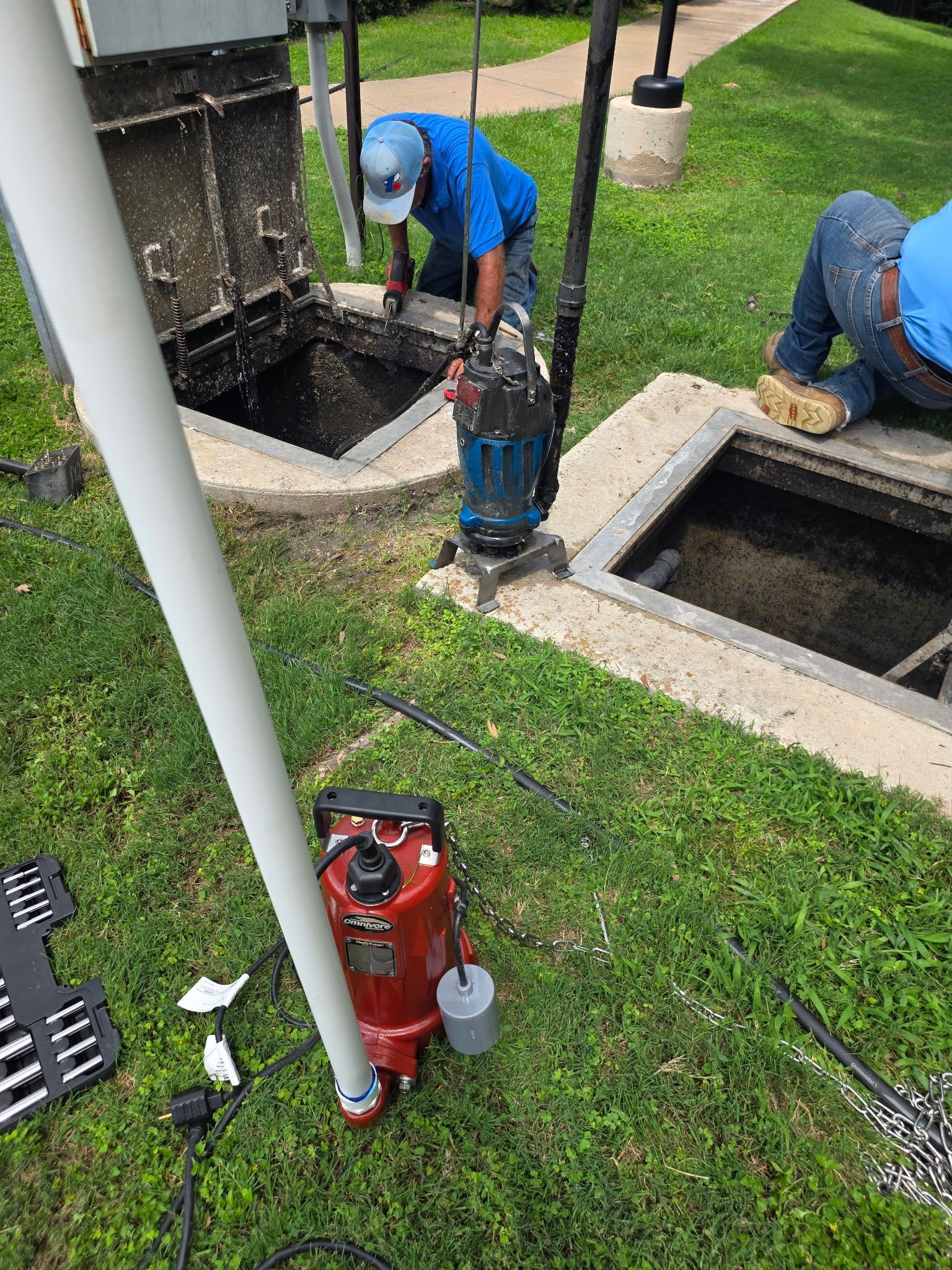 Concrete utility lid in dirt beside a green plastic ring and stone curb