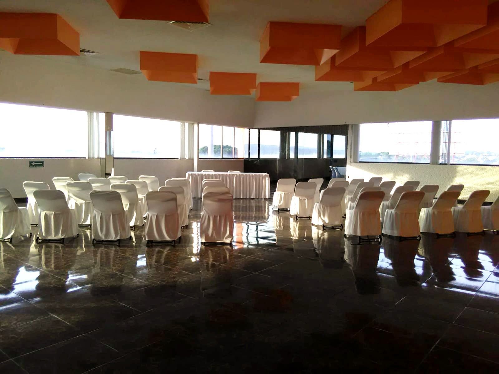 Una gran sala llena de sillas y mesas blancas.