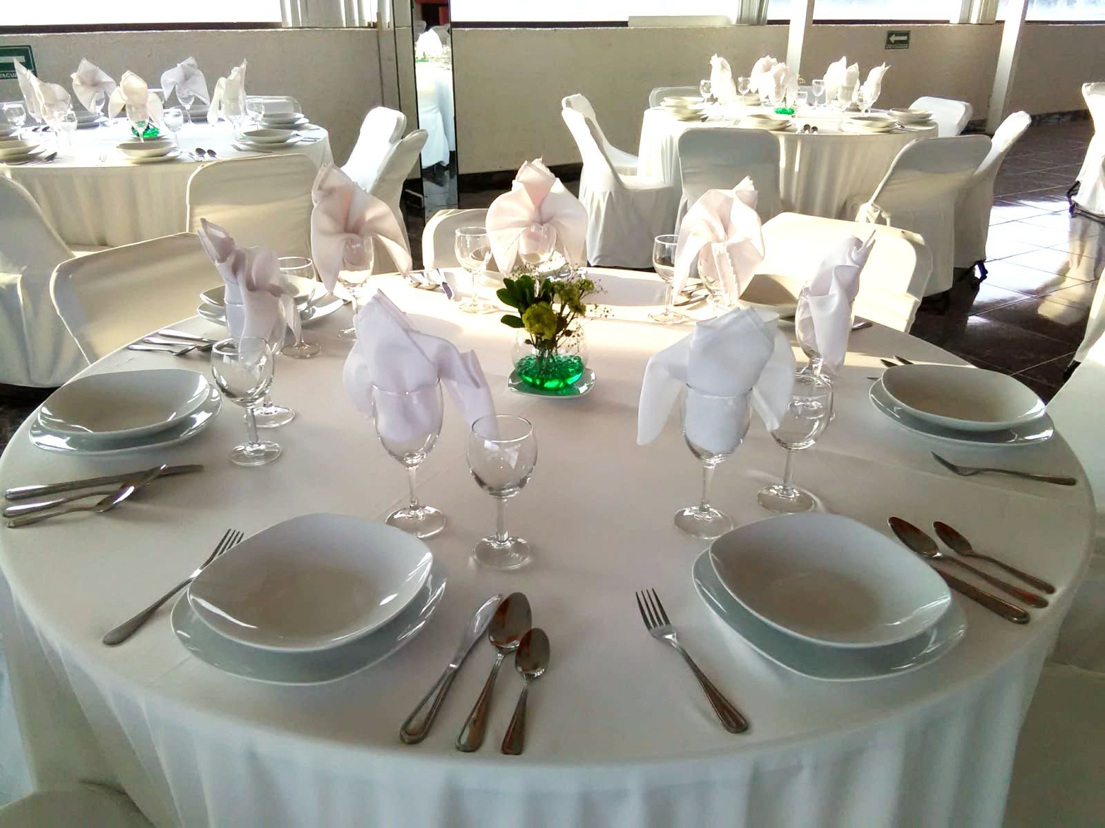 Una mesa con platos, utensilios y un jarrón con flores sobre ella en el HOTEL DE CUAUTLA.