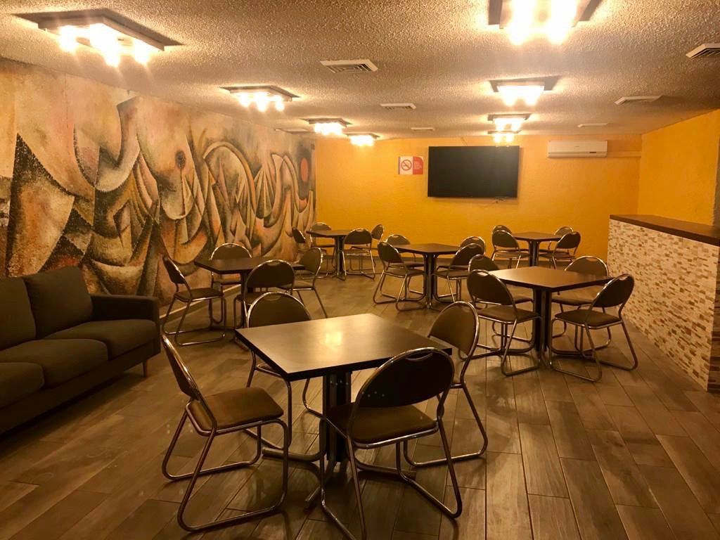 Sala grande del HOTEL DE CUAUTLA con mesas y sillas y un sofá.