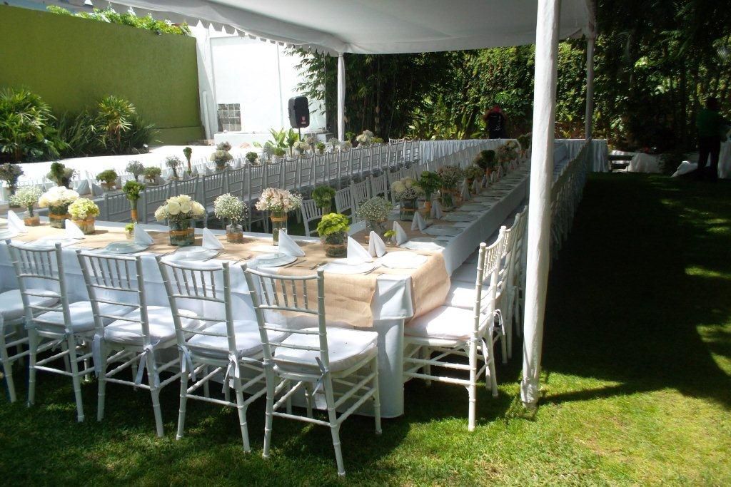 Una mesa larga y sillas debajo de una carpa en el césped en el HOTEL DE CUAUTLA.