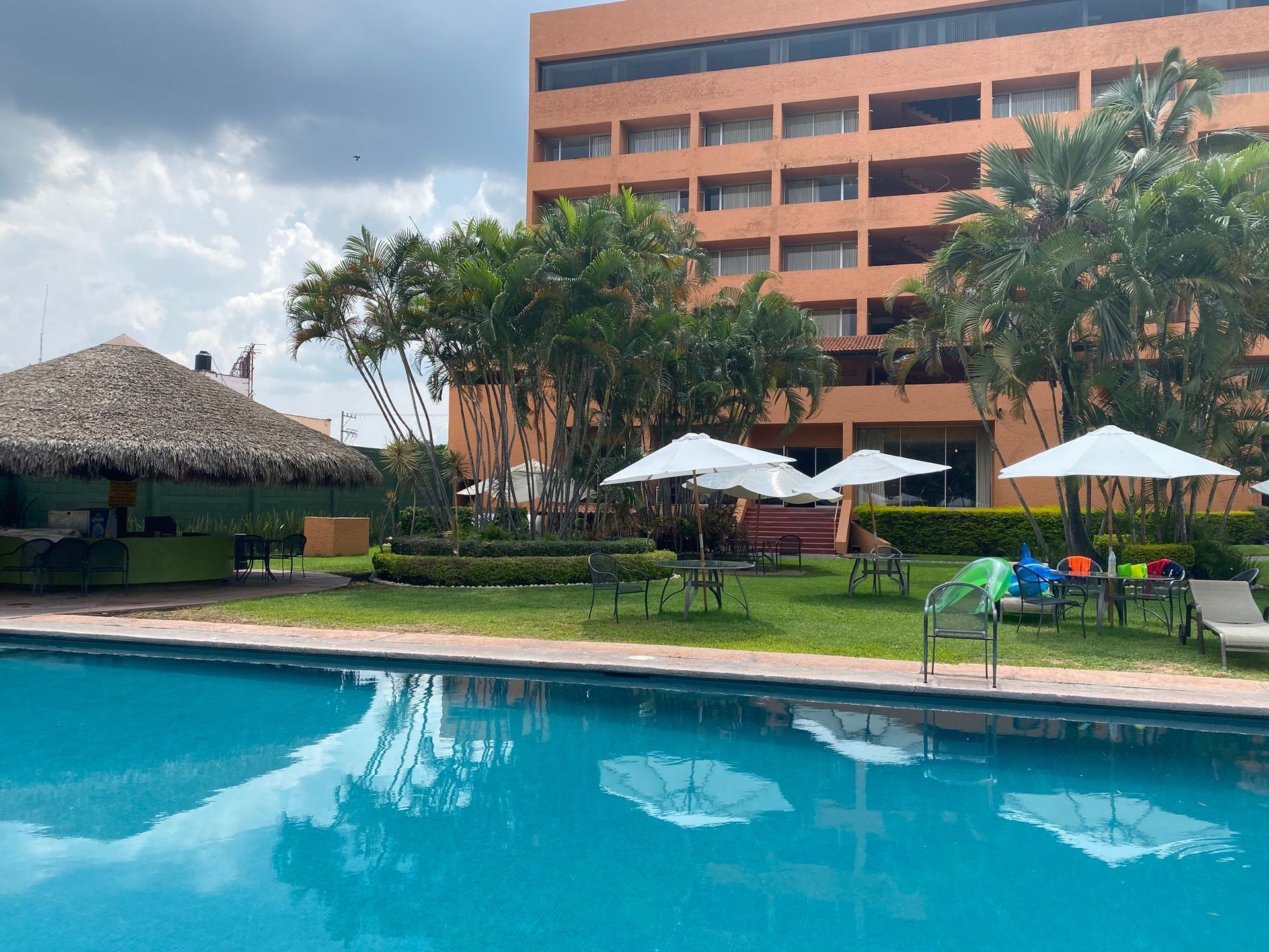 Una gran piscina rodeada de sillas y sombrillas frente a un gran edificio.