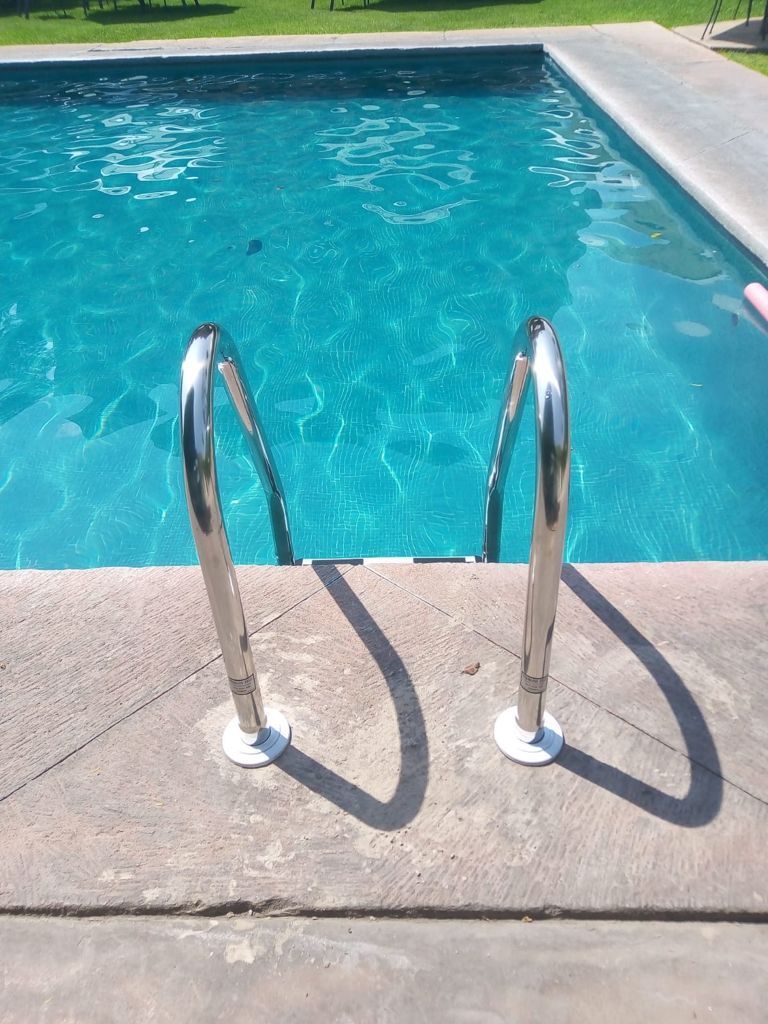 Una escalera de acero inoxidable que conduce a una piscina.