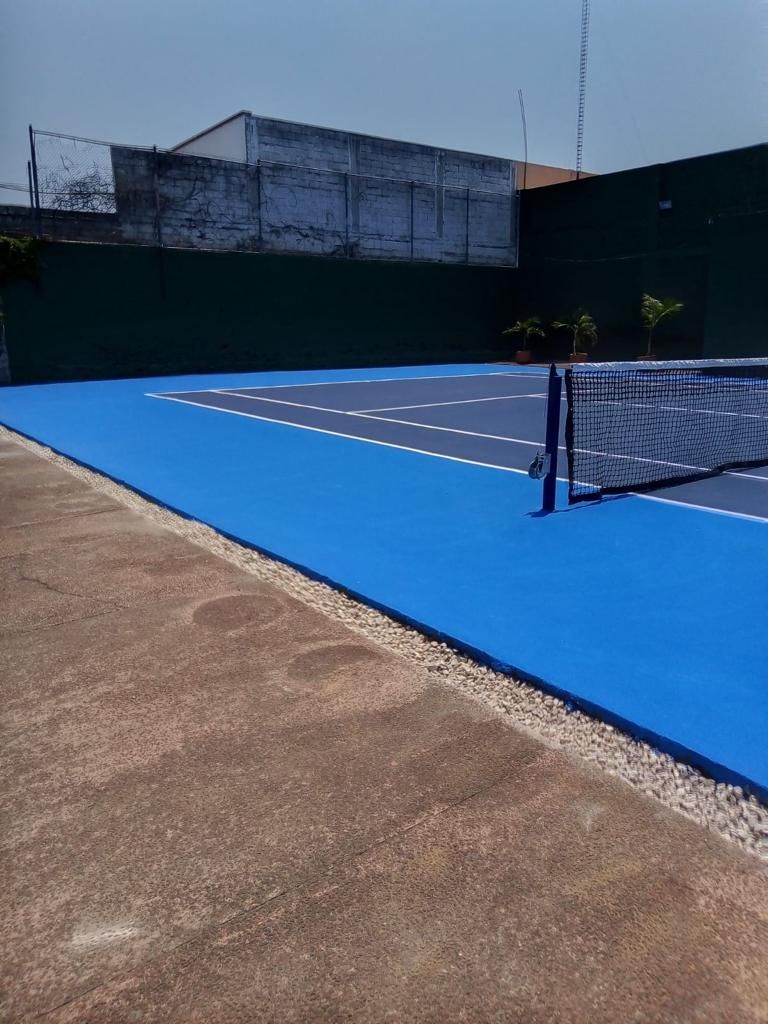 Una cancha de tenis azul con una red y el HOTEL DE CUAUTLA de fondo.