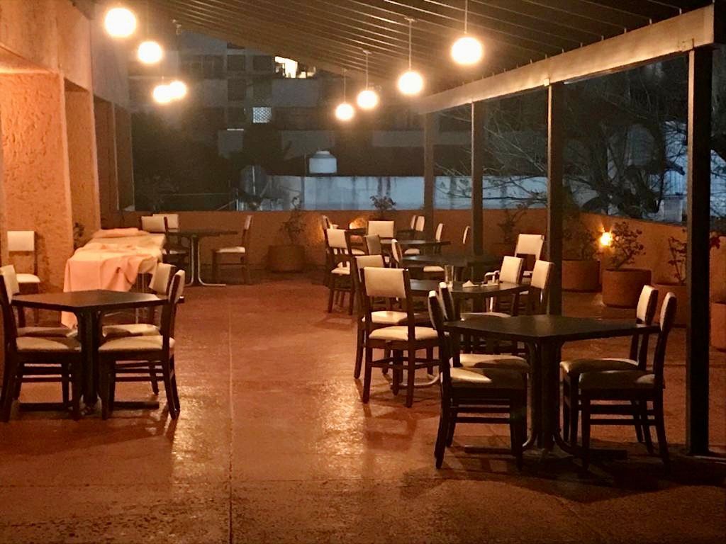 Restaurante del HOTEL DE CUAUTLA lleno de mesas y sillas por la noche.
