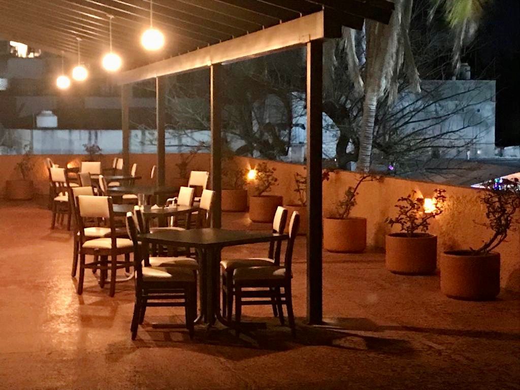 Restaurante del HOTEL DE CUAUTLA con mesas y sillas bajo un dosel por la noche.