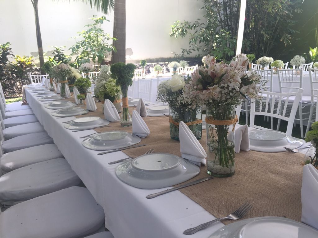 Una mesa larga con platos y jarrones con flores sobre ella en el HOTEL DE CUAUTLA.