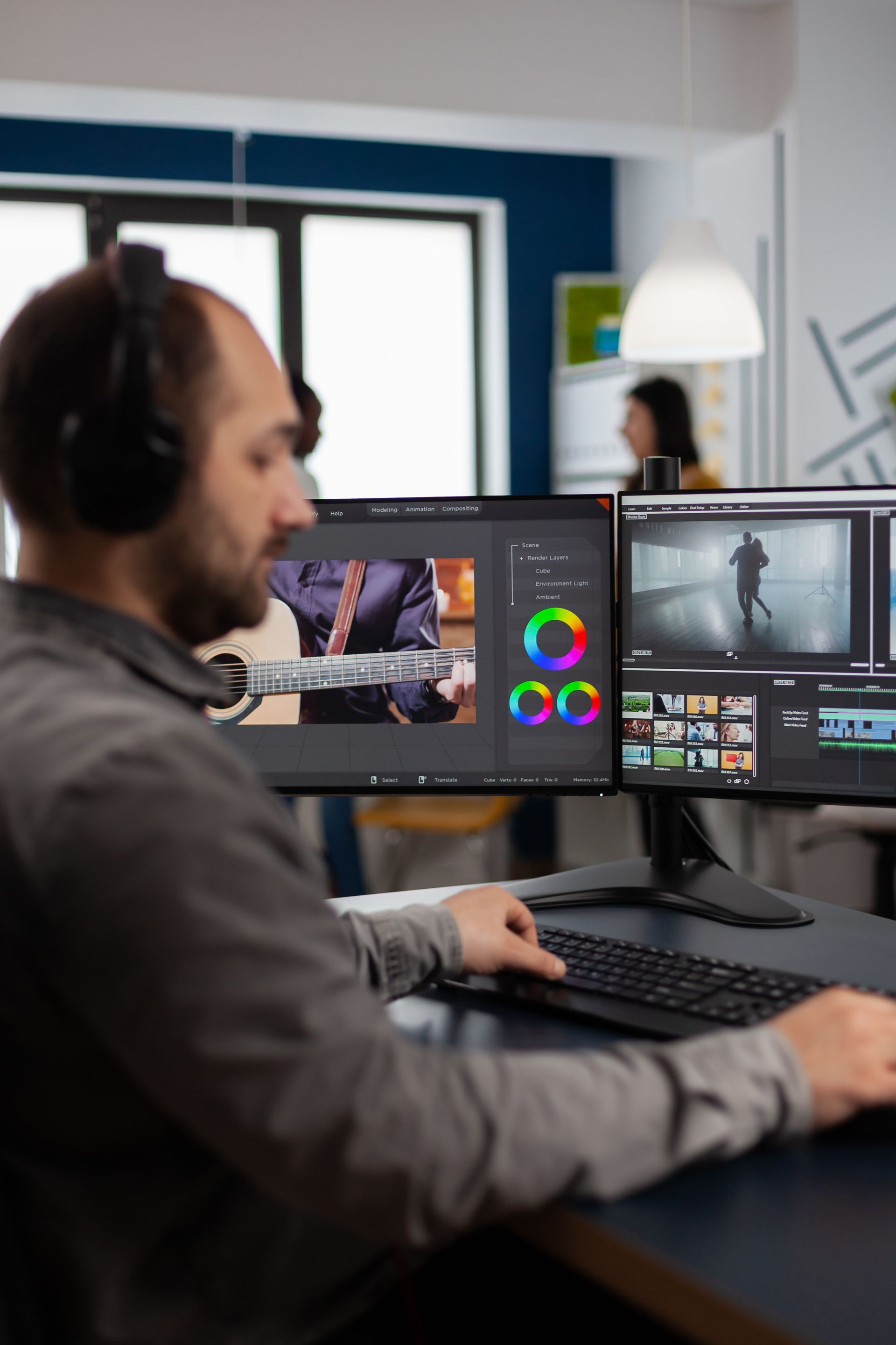 A man wearing headphones is sitting at a desk in front of two computer monitors.
