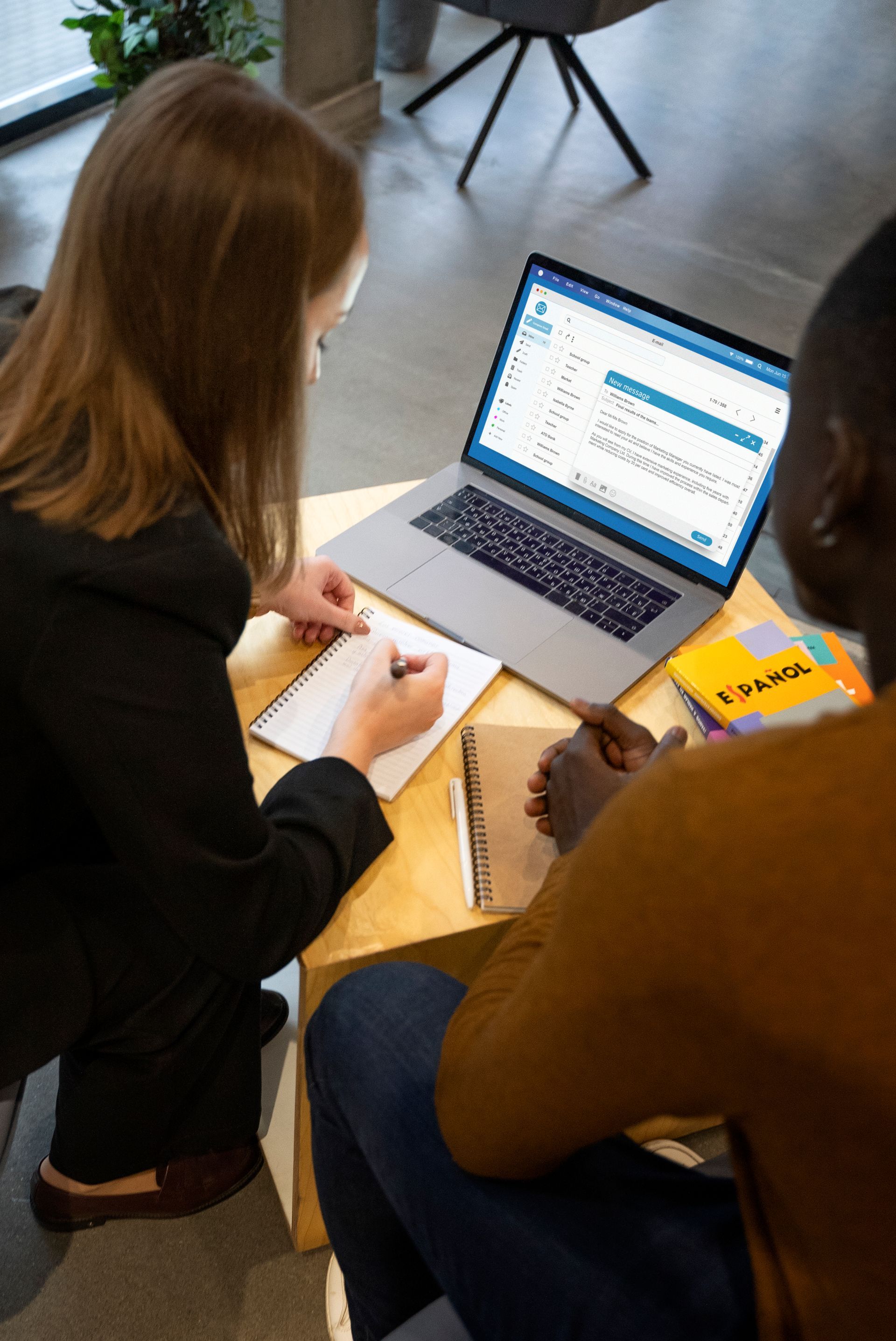 A man and a woman are sitting at a table with a laptop.