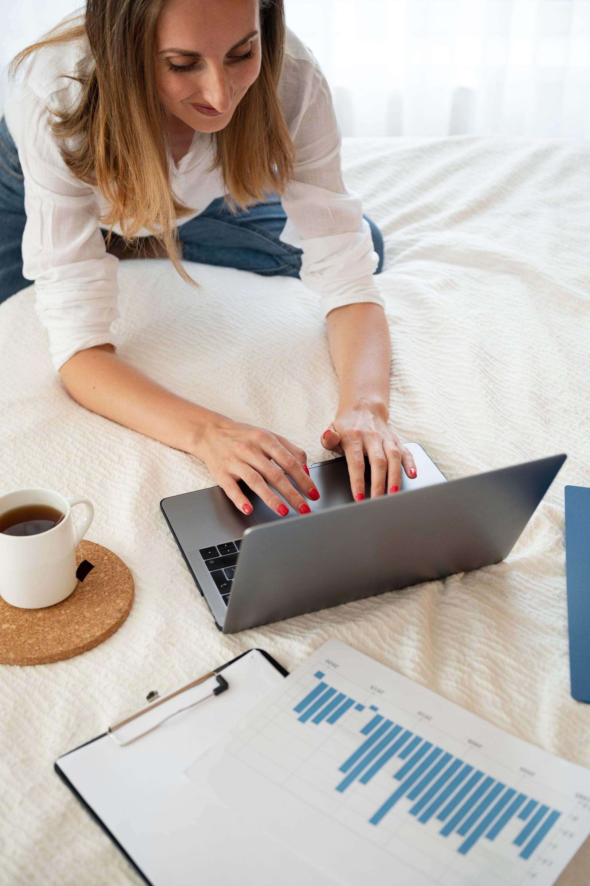 A woman is laying on a bed using a laptop computer.