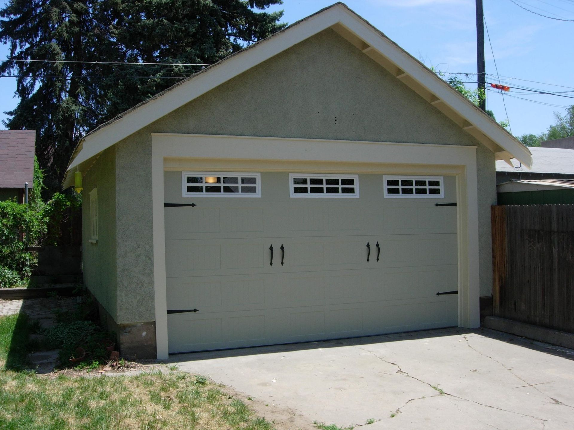 Tan stucco garage with a gray concrete driveway.