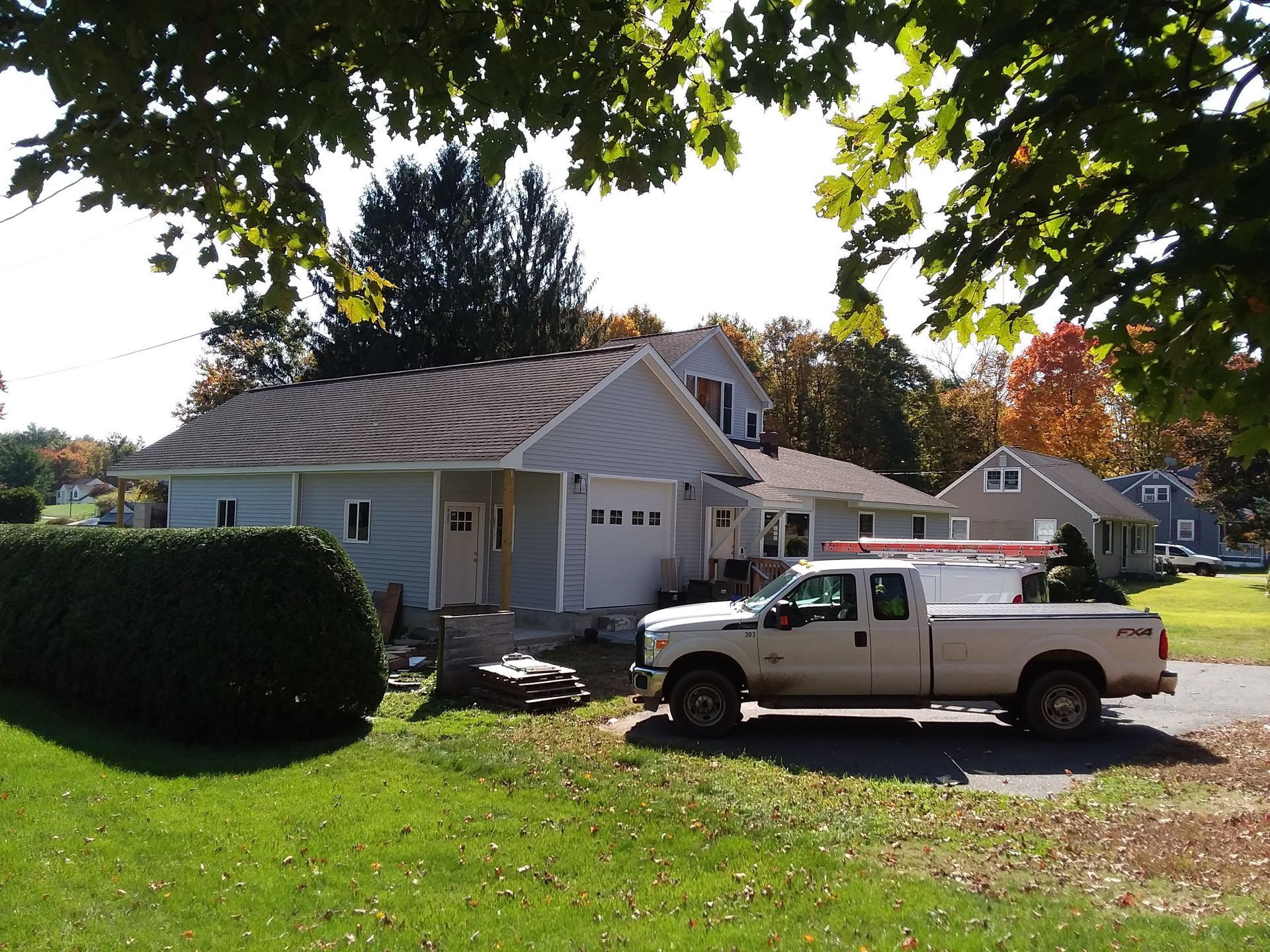 Light blue house with white garage doors, a white pickup truck parked in the driveway.