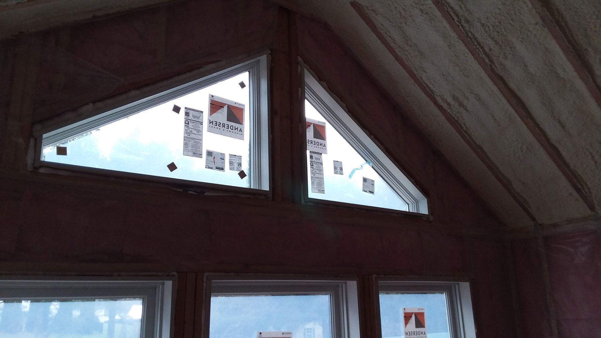 Interior view of a building with two triangular windows and three rectangular windows below.