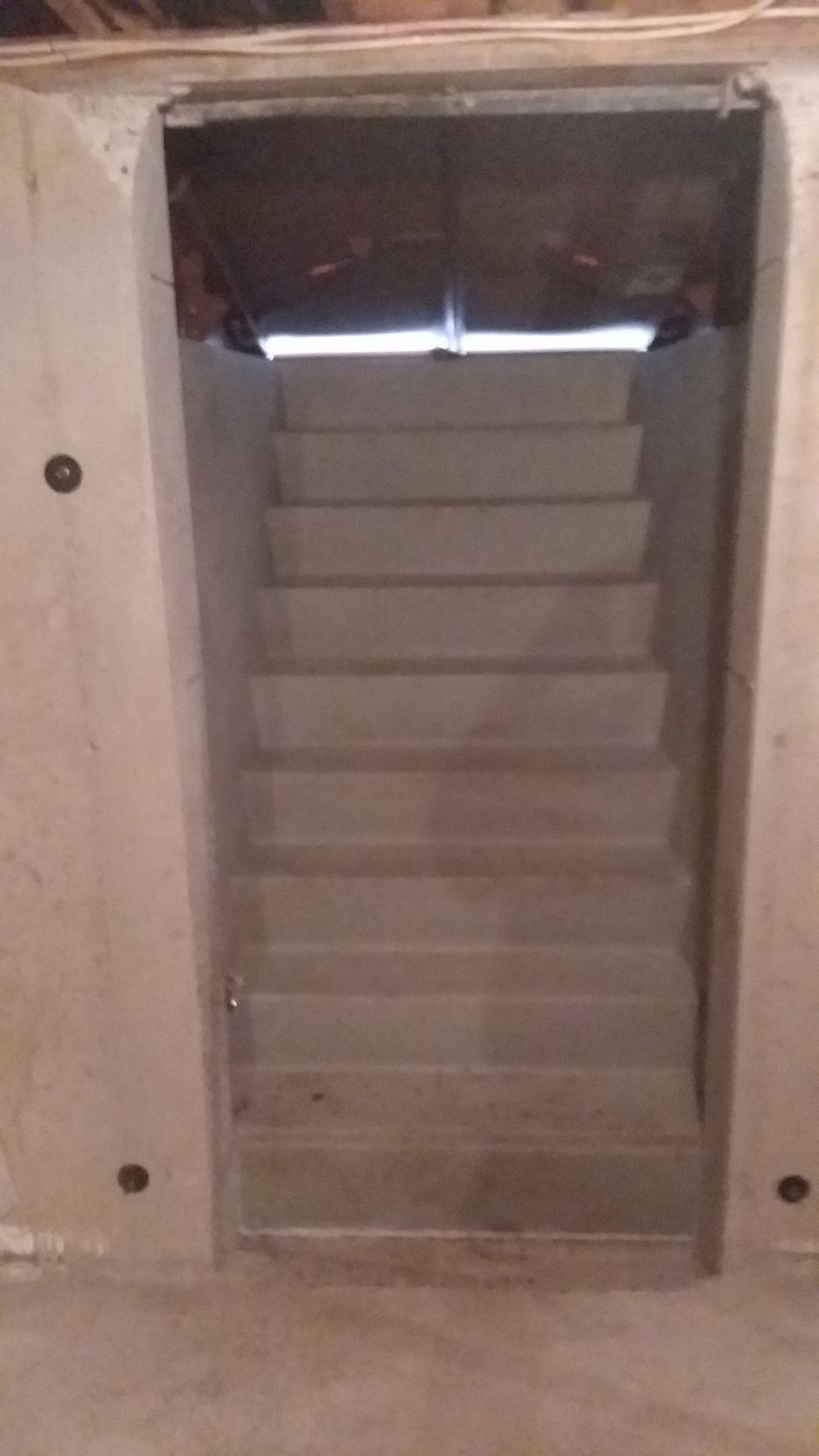 Staircase leading upwards within a concrete framed opening; natural light at the top.