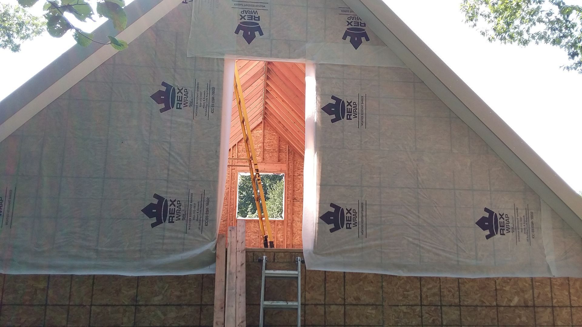 Exterior of a building under construction, showing framing, sheathing, and a partially open doorway.