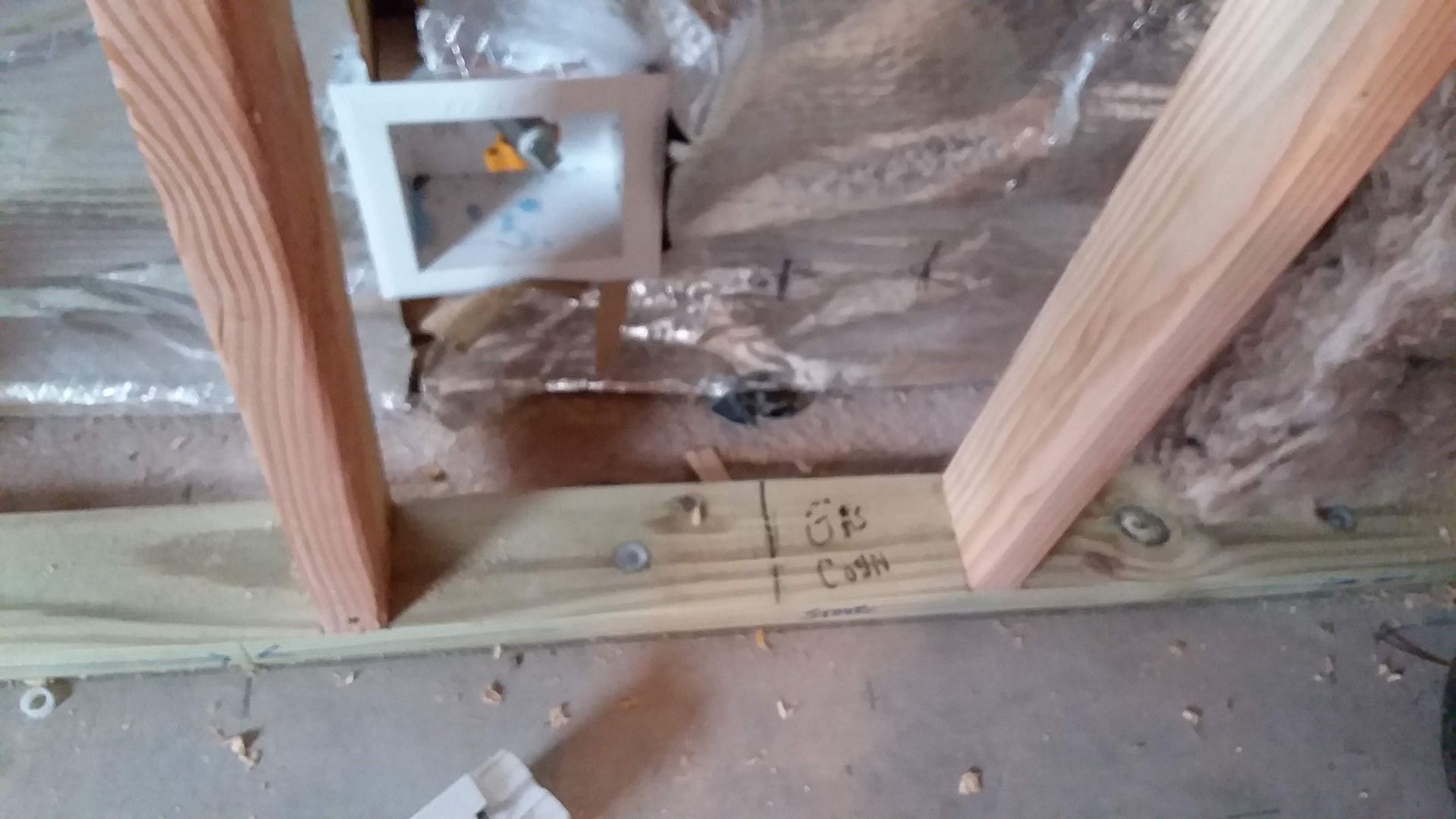 Wooden frame construction with vertical and angled supports, and a wall outlet.