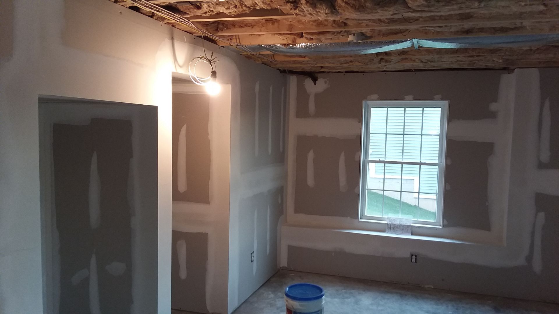 Room under construction with drywall installed. Window, door frame visible.