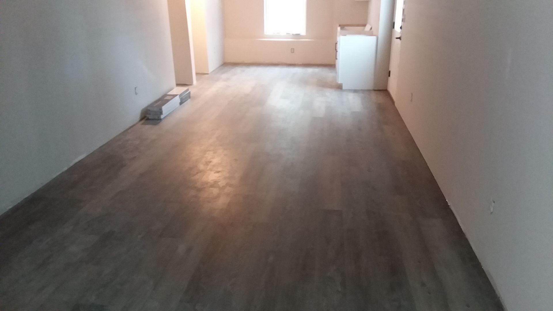 Empty room with gray flooring and light gray walls; small window at the back.