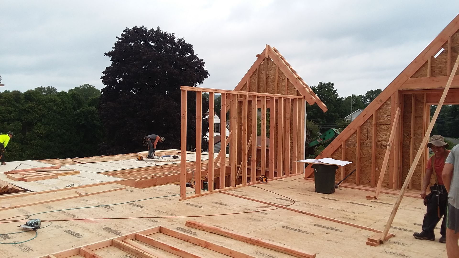 Construction site: wooden frame building in progress on a roof, with workers present.