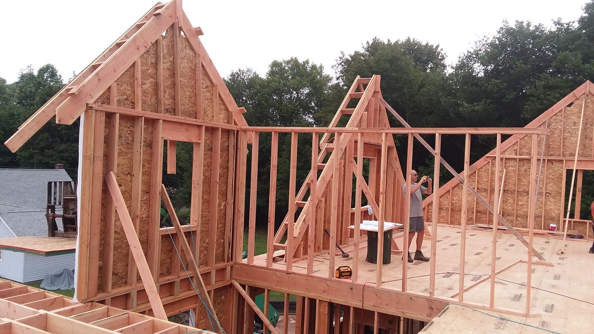 Construction of a building's wooden frame; a person works inside the incomplete structure.