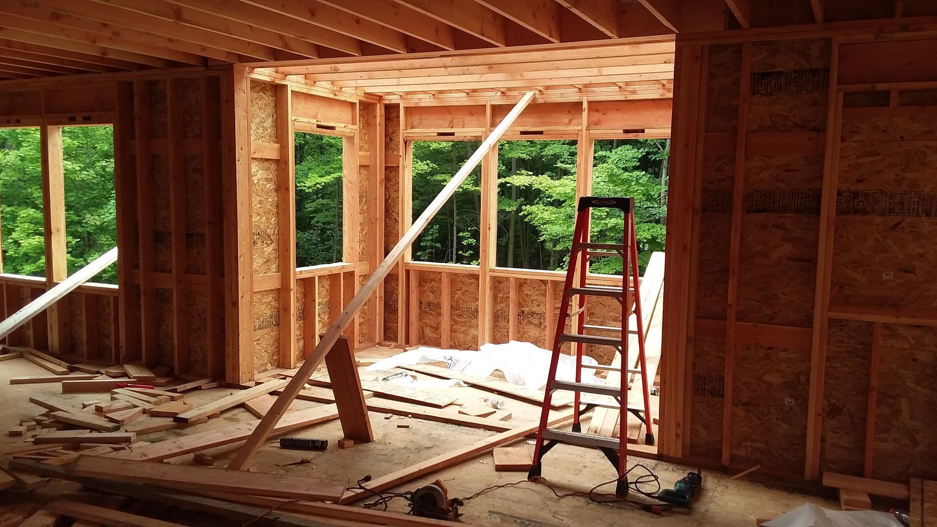 Interior of a house under construction. Wooden framing with windows and a ladder.