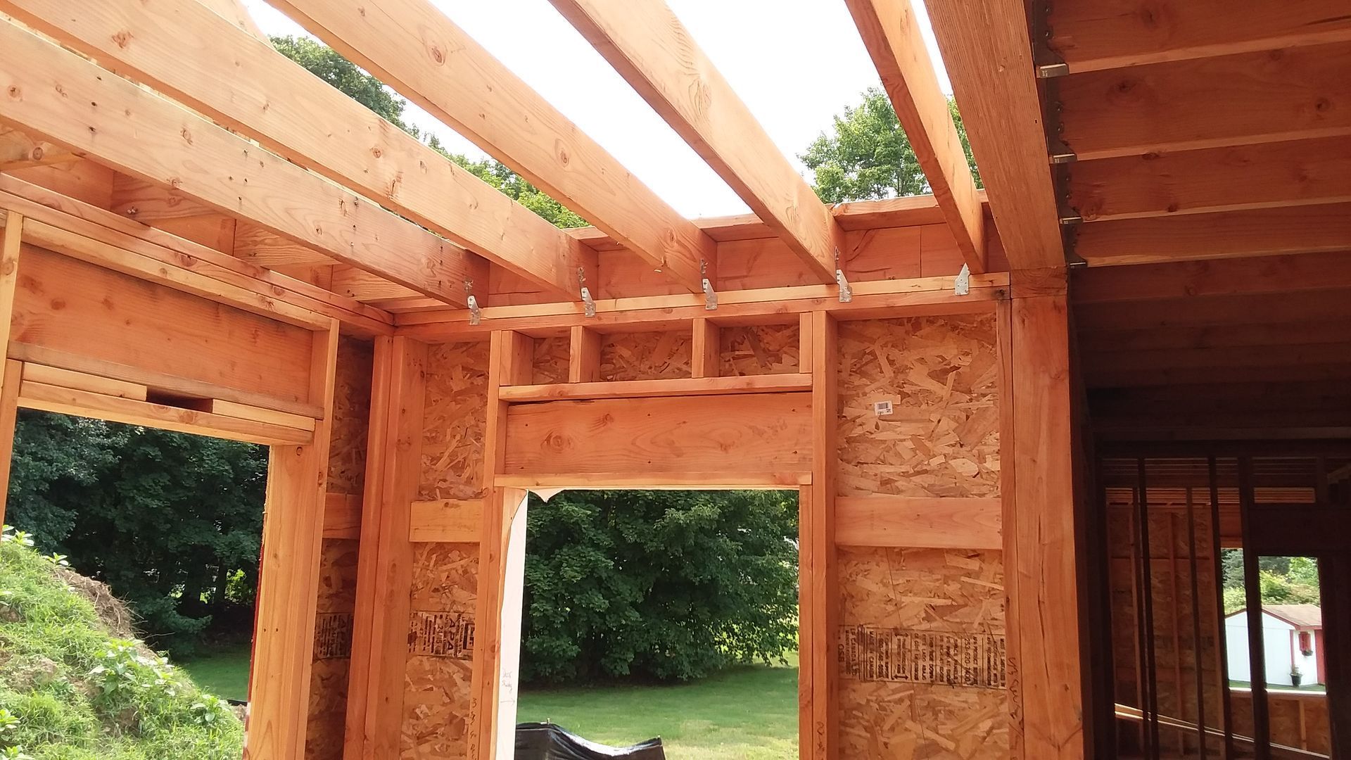 Interior wooden framing of a building under construction, showing beams and door frames.