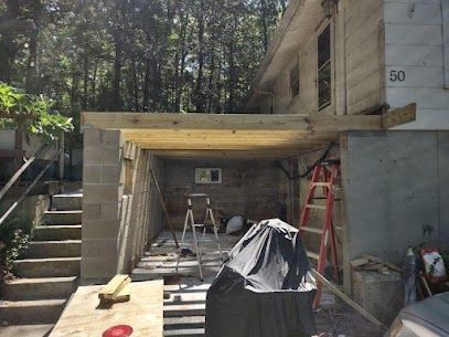 Construction of a covered porch. Wooden beams and cinder block walls support the roof; a ladder is present.