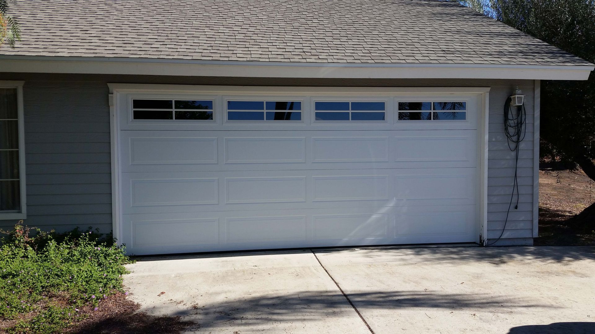 White garage door with windows above; house exterior.