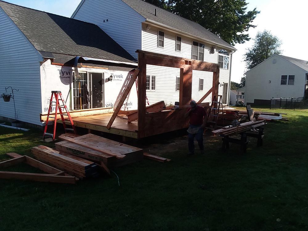 Construction of a wooden deck attached to a house; person working; green lawn.