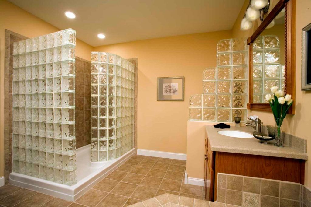 Bathroom with shower and vanity. Features glass block walls, tan walls and flooring, and wood cabinetry.