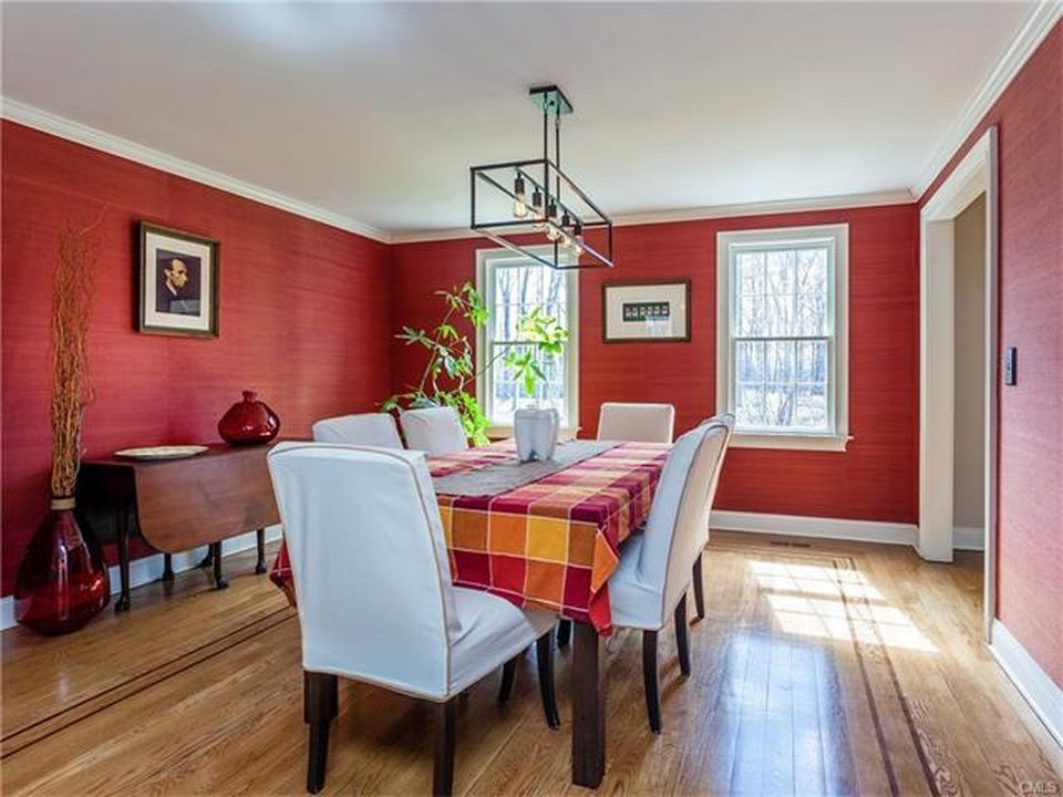Dining room with red walls, table set for six, hardwood floor, natural light.