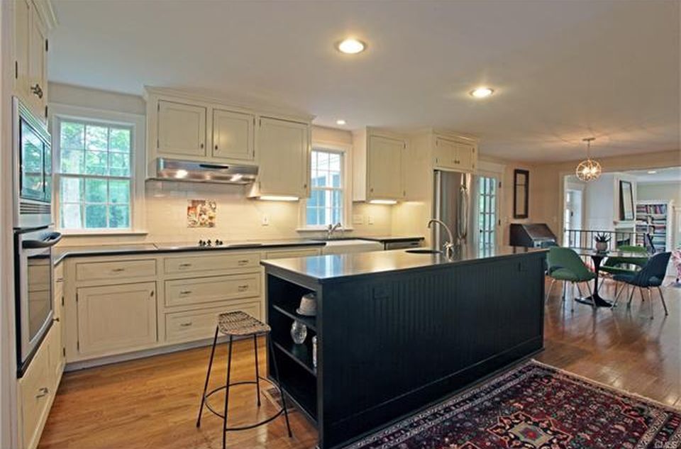 Kitchen with cream cabinets, black island, stainless steel appliances, and hardwood floors.