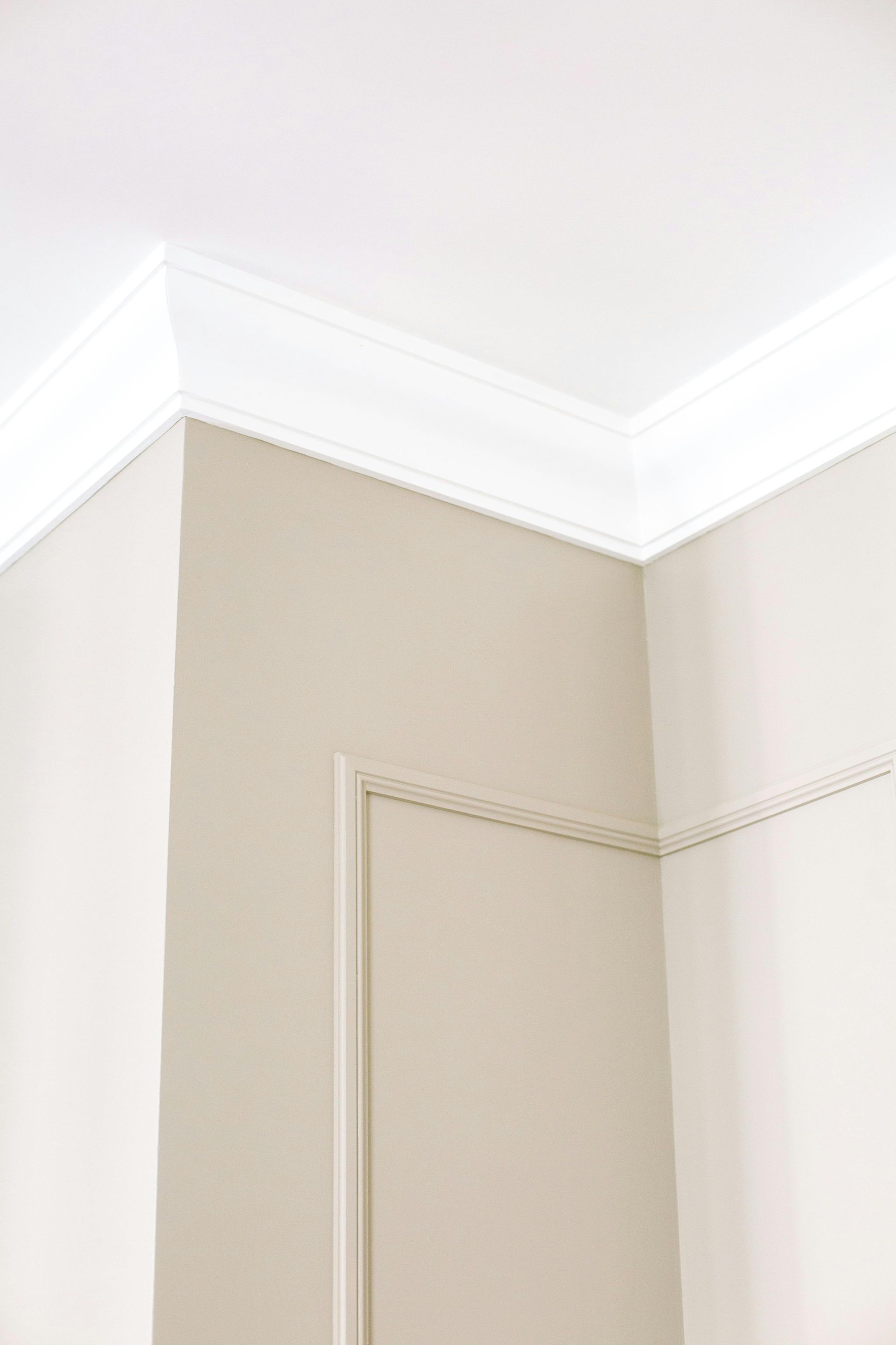 Corner of a room with white crown molding and beige walls.