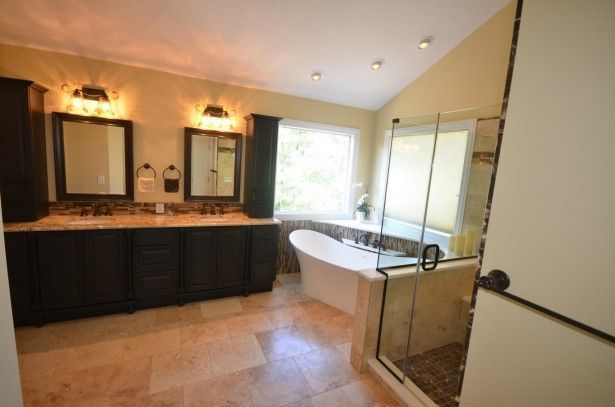 Elegant bathroom with dark cabinets, a soaking tub, and a glass shower.