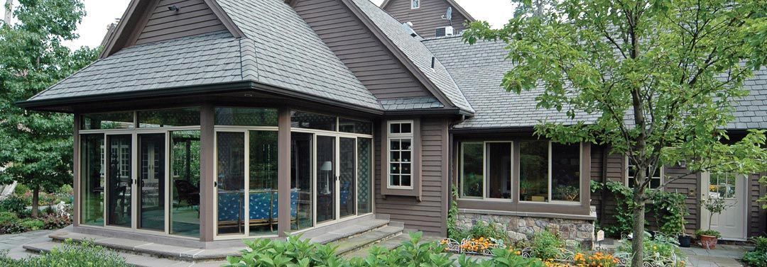 Brown house with screened porch and garden.