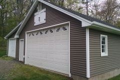 Brown and white garage with a large overhead door and a small window.